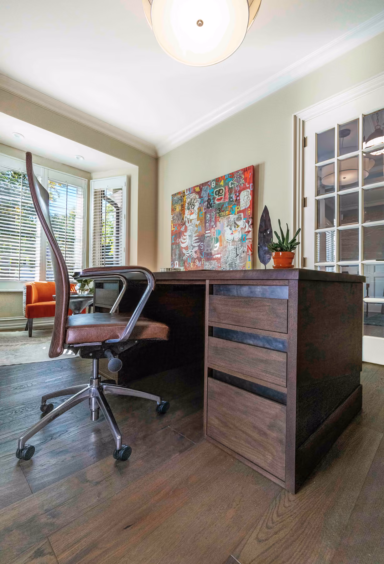 Home office desk detail with a leather office chair and a colorful abstract painting