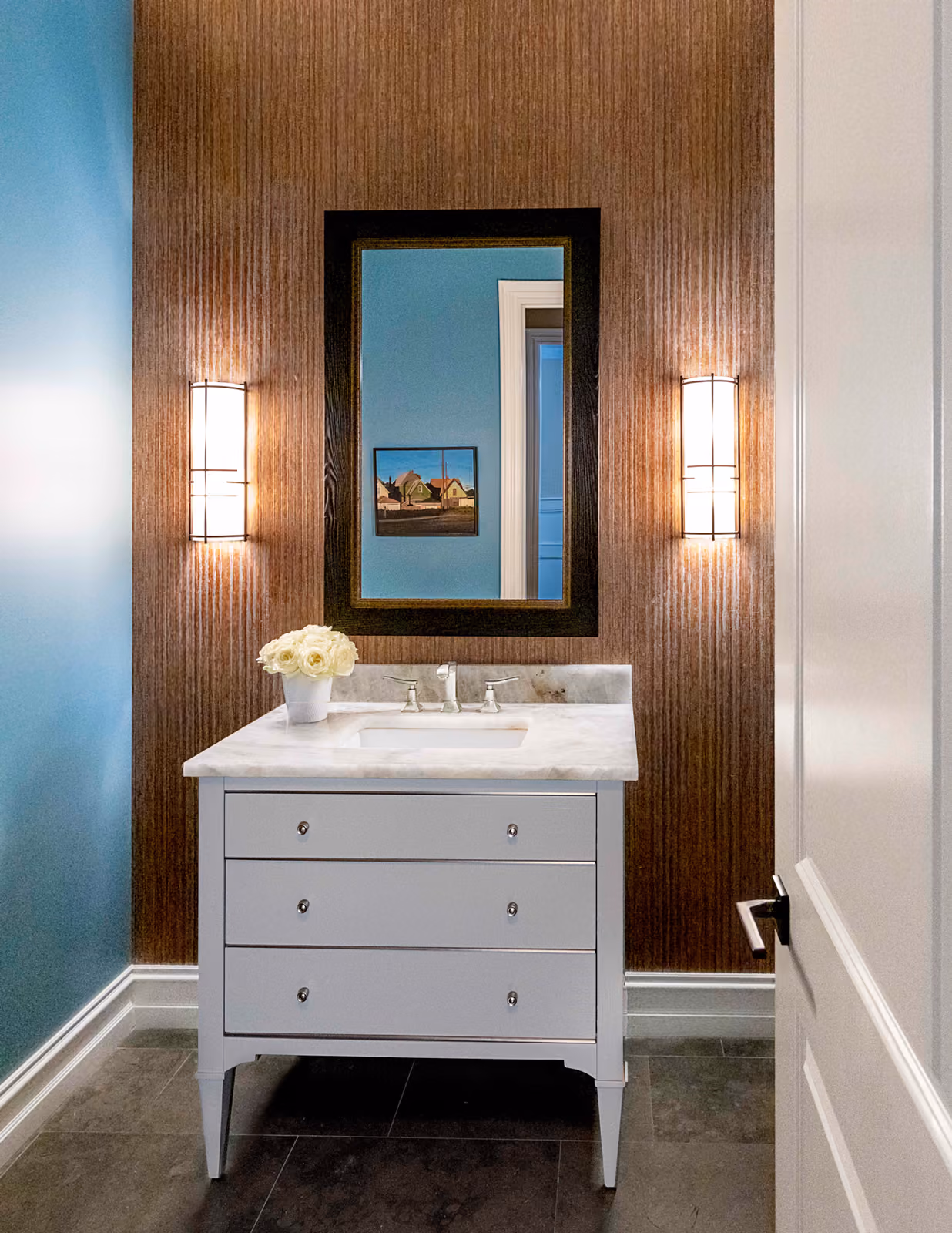 Powder room with wood-grain textured wallpaper, a blue accent wall, and a white vanity with marble top