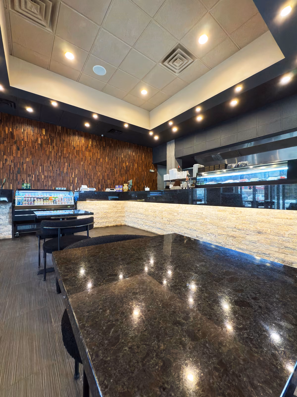 Dining room with a black tray ceiling, granite tables, and an open kitchen pass-through