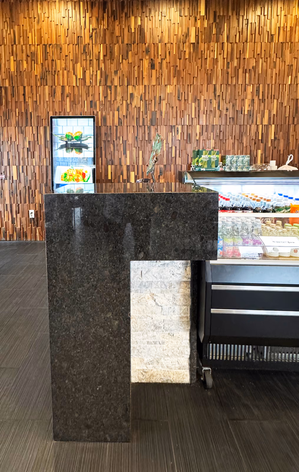 Host stand with a dark granite pedestal, stone tile inset, and digital menu screen