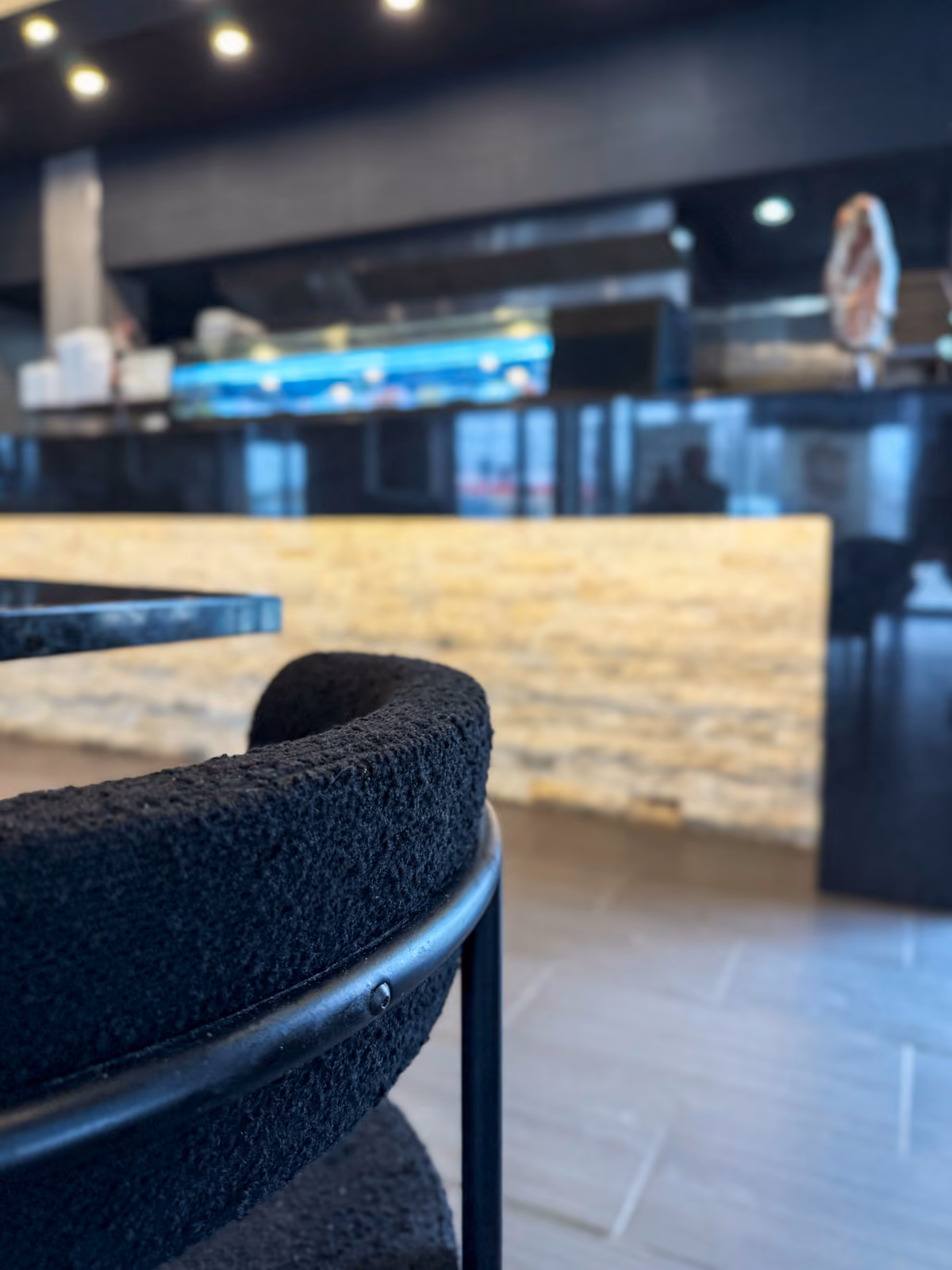 Detail of a black bouclé bistro chair with the glowing stone counter blurred in the background
