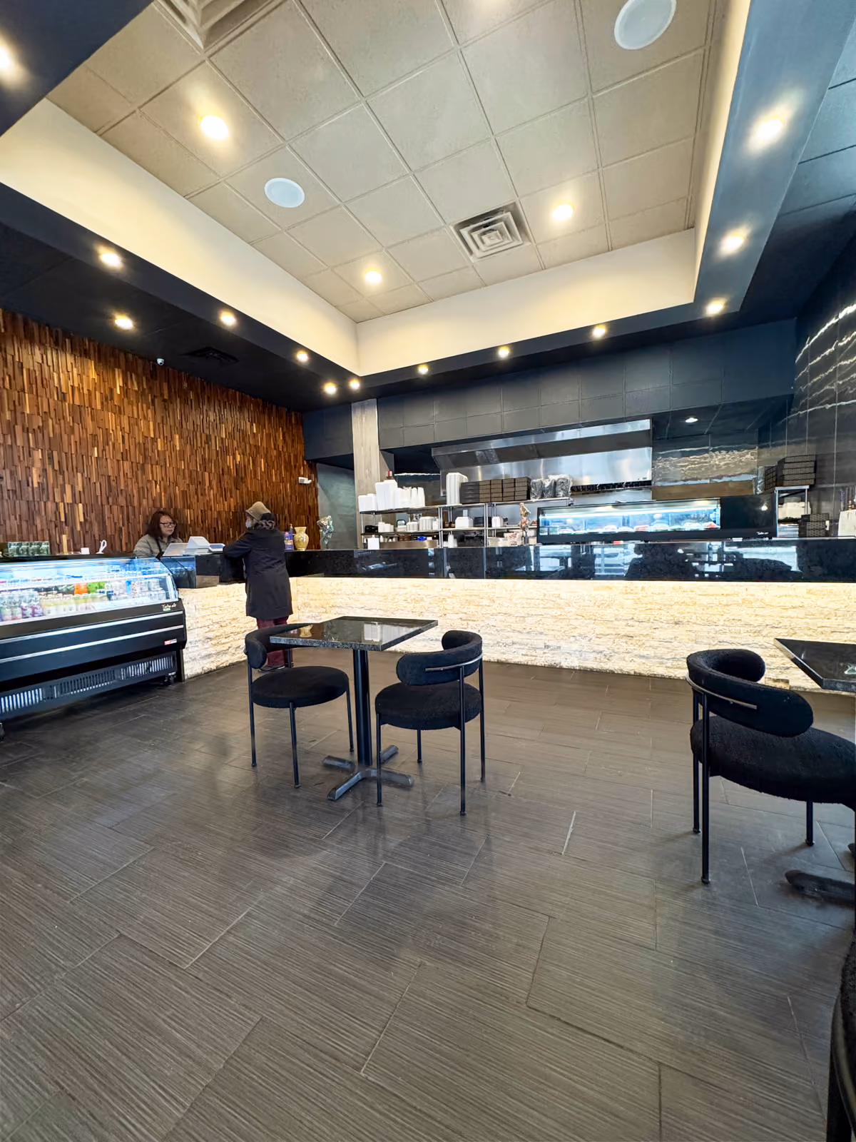 Dining room with a black tray ceiling, glowing stone counter front, and an open kitchen