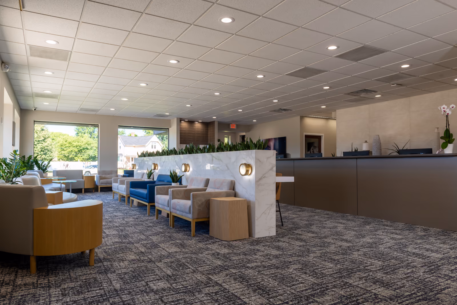 Wide view of the waiting room with a marble planter wall, patterned carpet tile, and the reception desk beyond