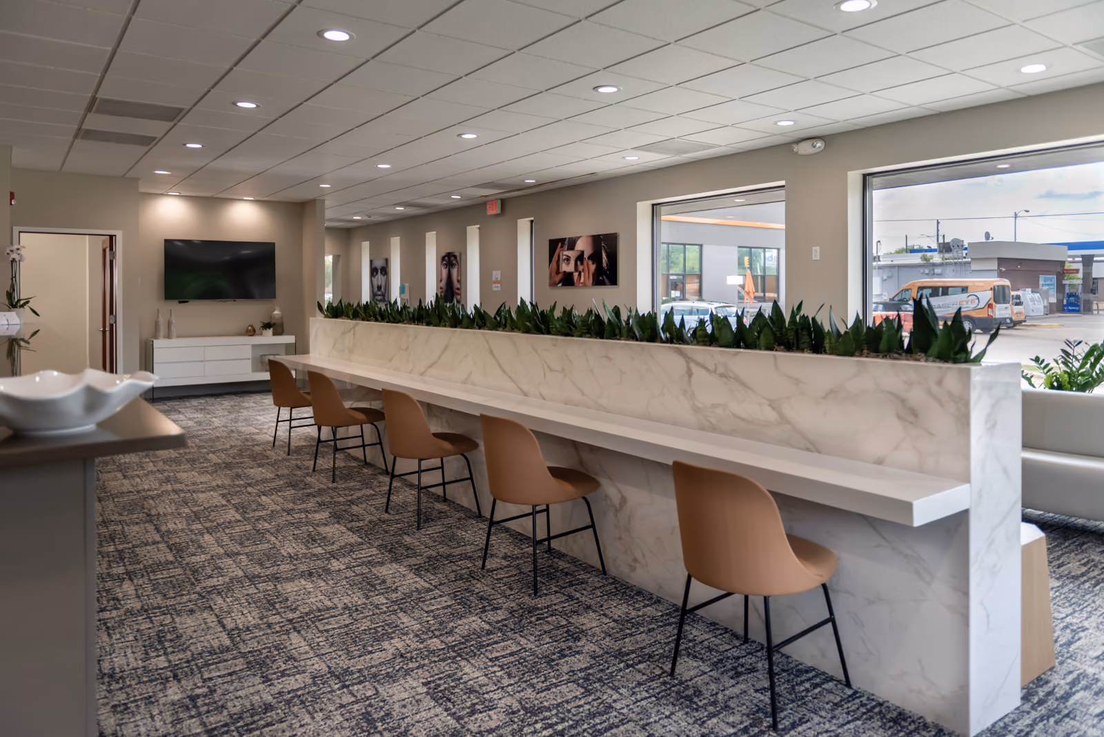 Workstation counter with cognac task chairs along a marble waterfall counter with integrated planters