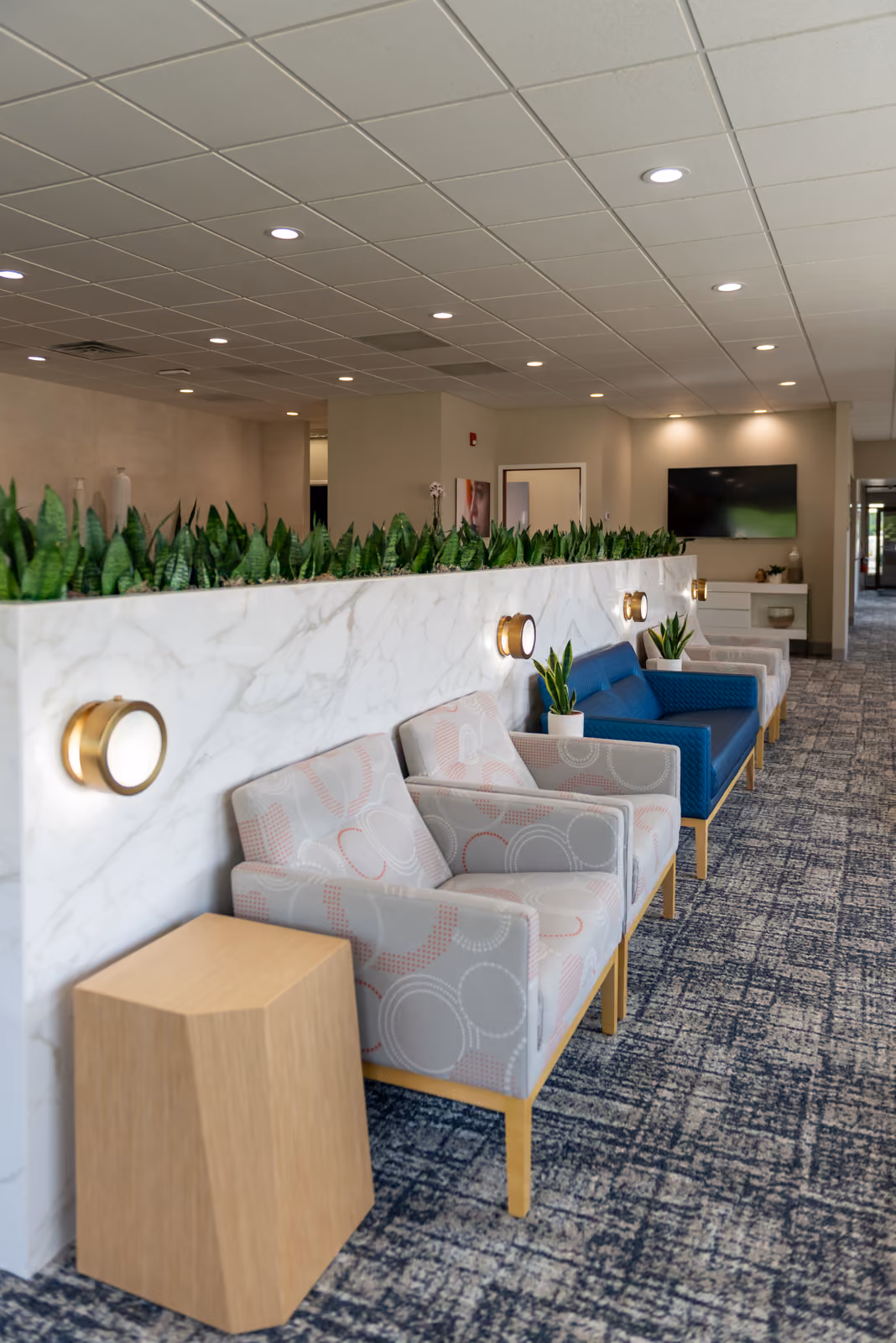 Waiting room chair row against the marble planter wall with brass sconces