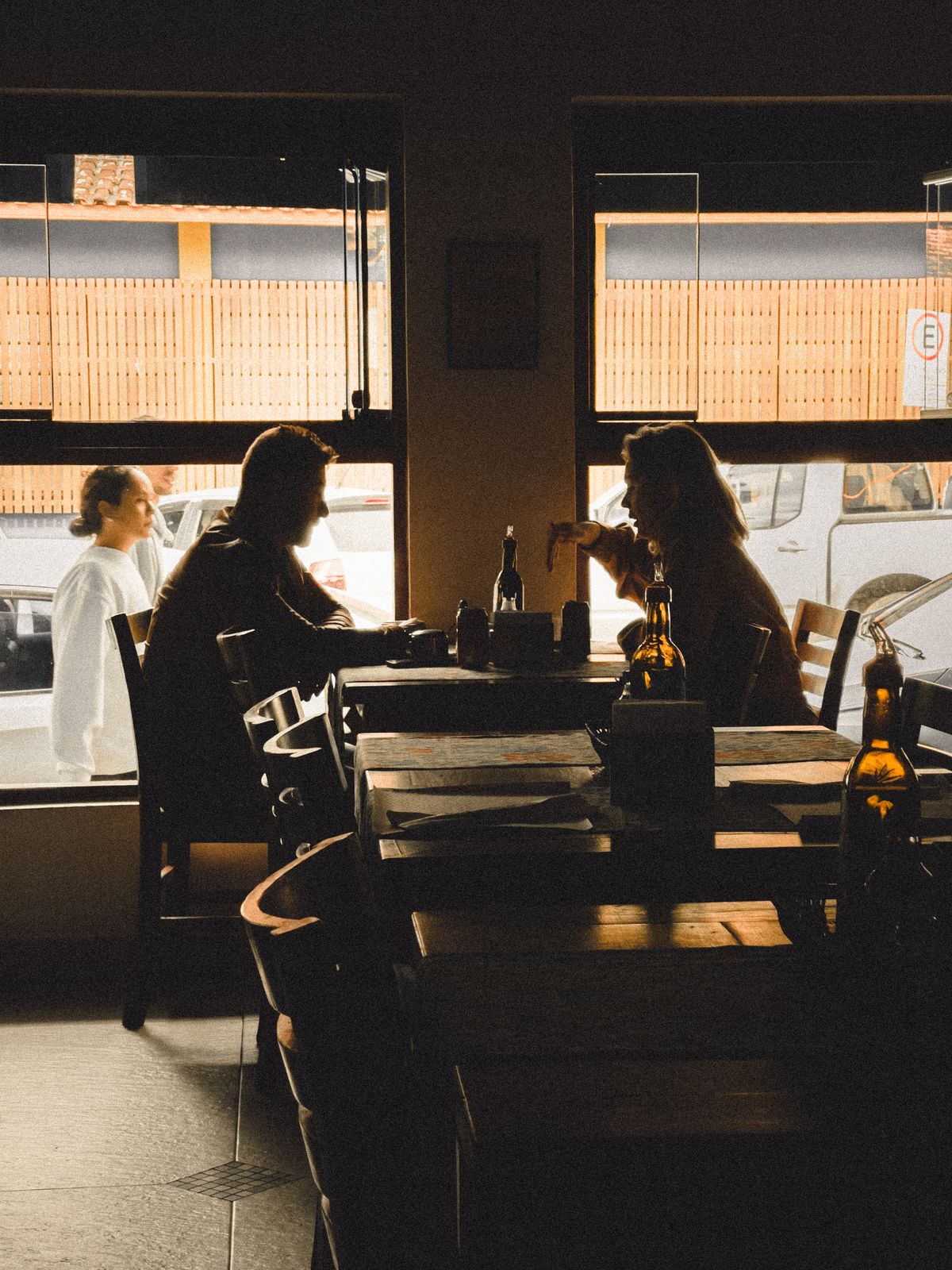 Two silhouettes in conversation at a sunlit café window