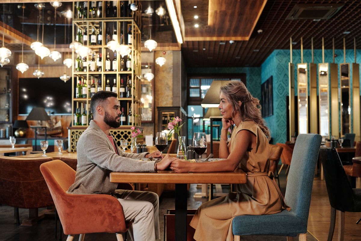 A couple enjoying a candlelit dinner with wine in an elegant restaurant