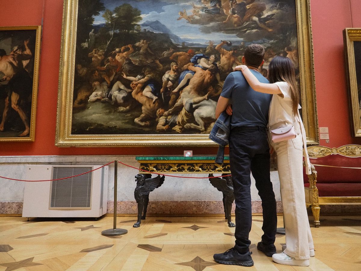 A couple admiring a large classical painting in an art gallery