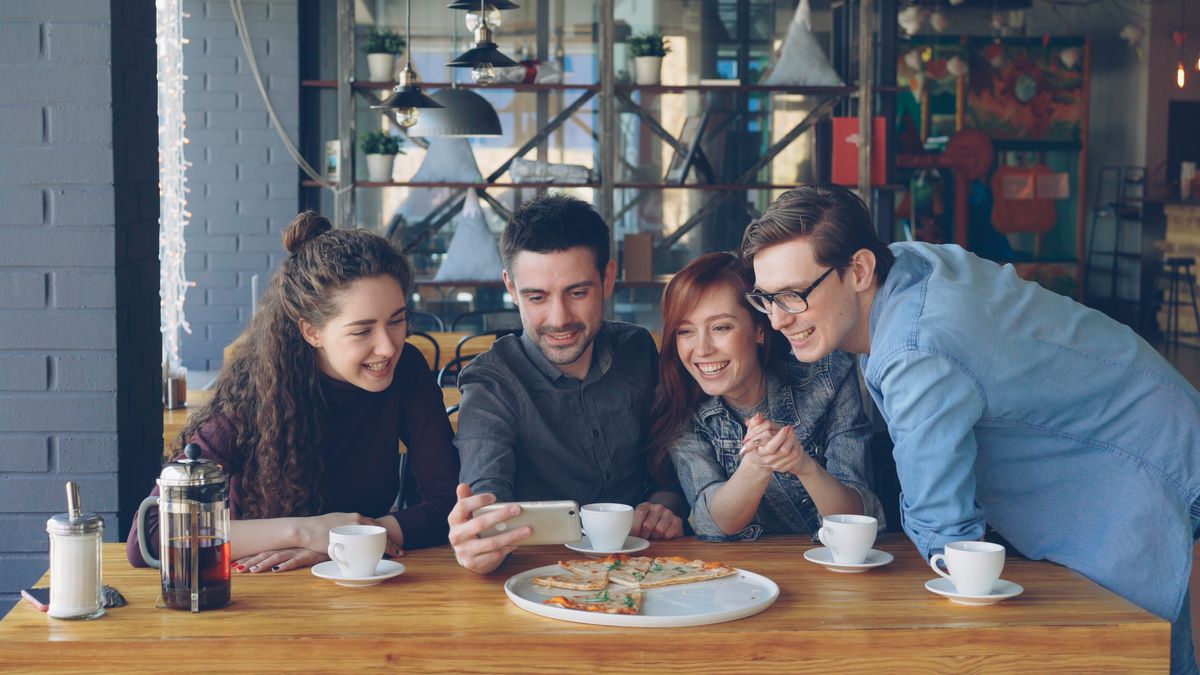 Four friends sharing coffee and laughter at a café table