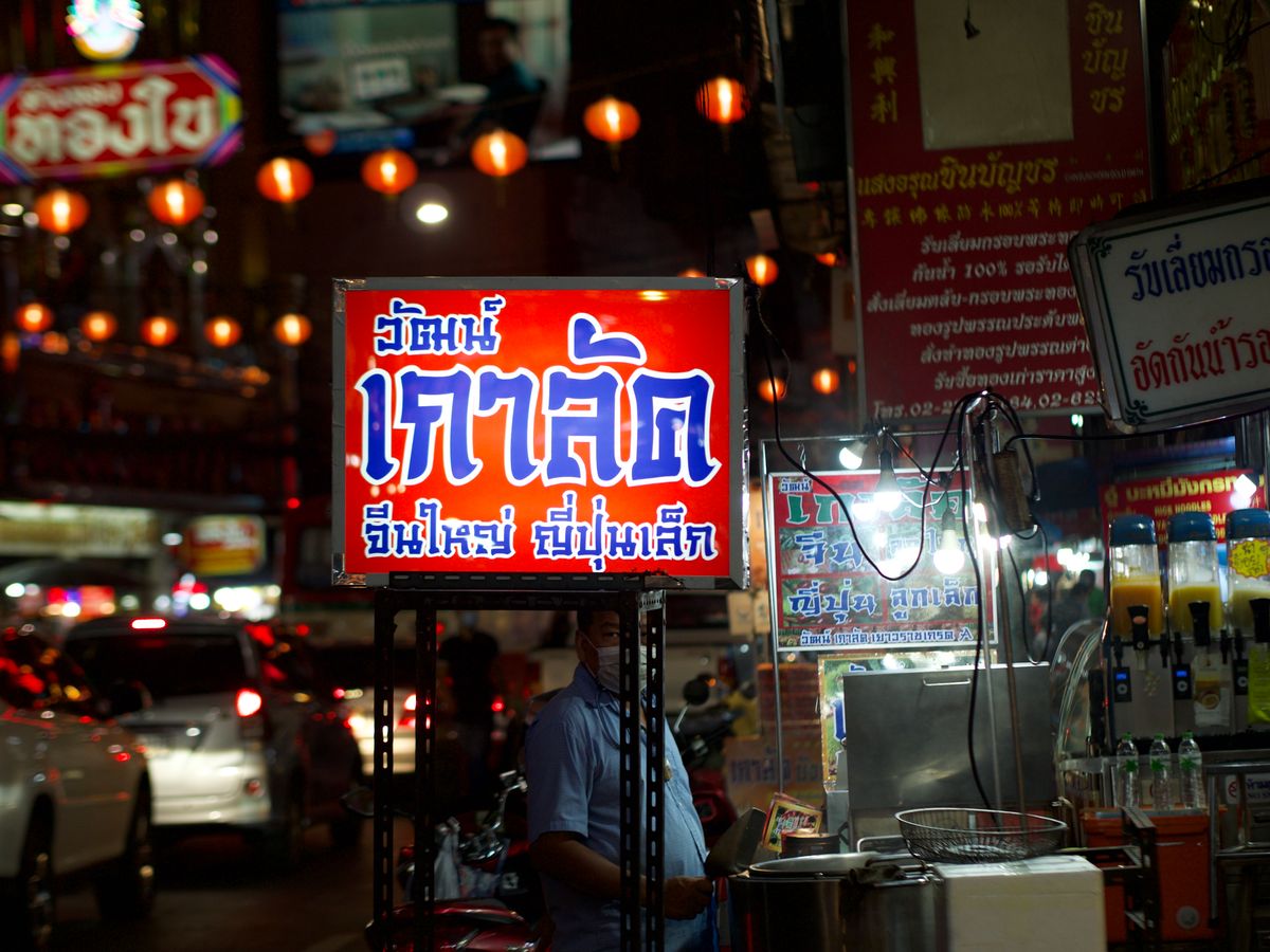 A Bangkok street at night, lit by market stalls and signage