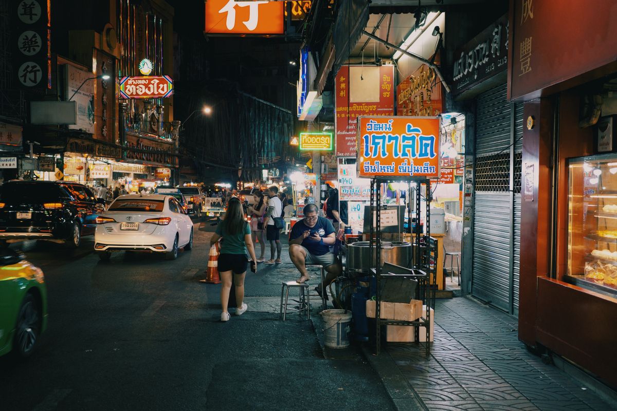 Neon signs above a busy Bangkok night market