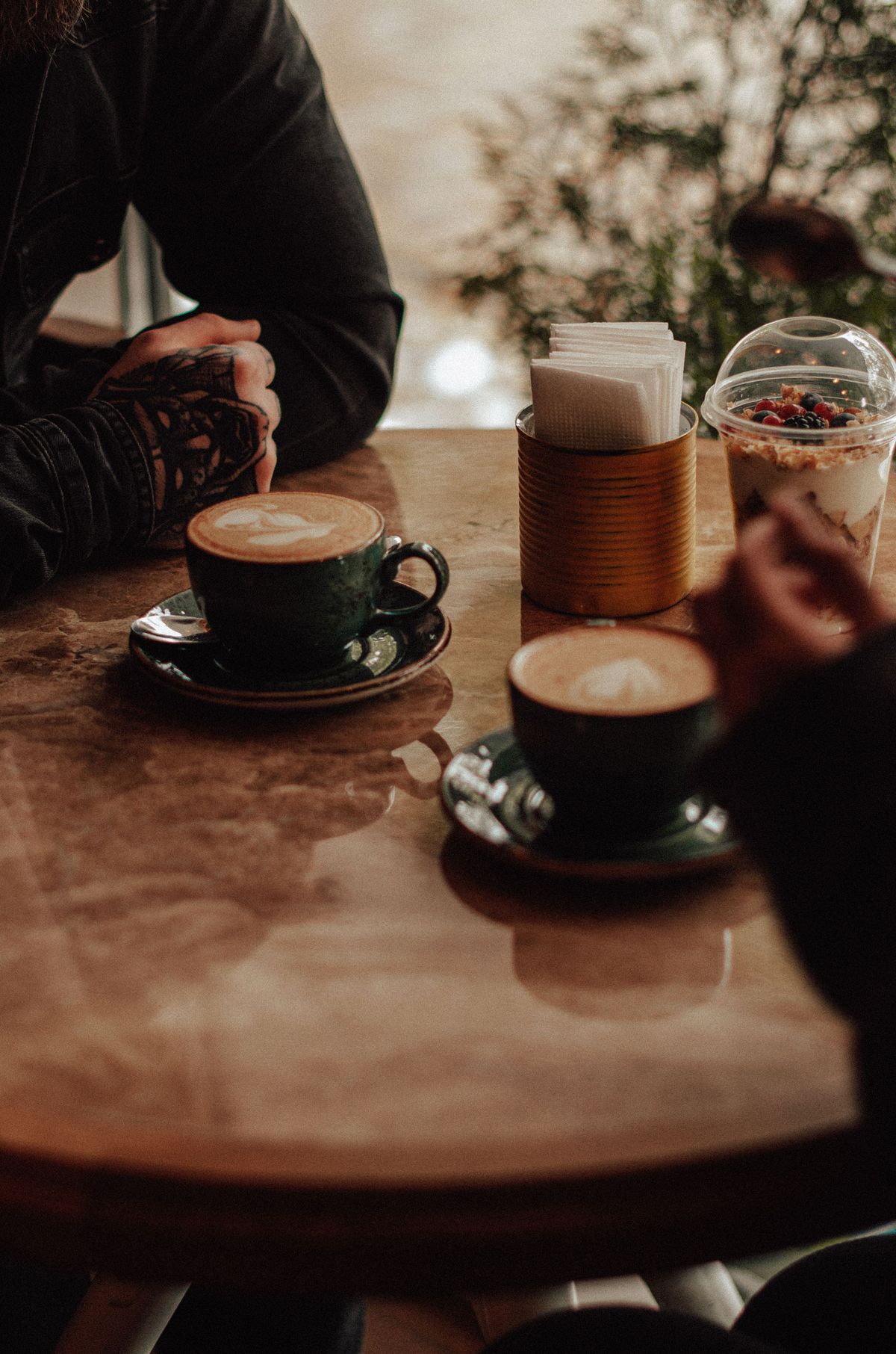 Two people talking over cappuccinos in a cosy café