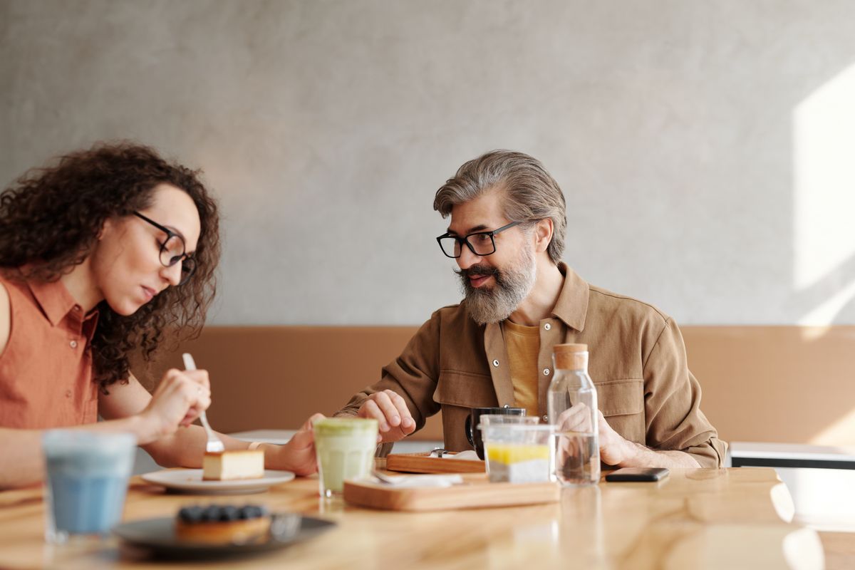 A pair sharing desserts and drinks across a café table