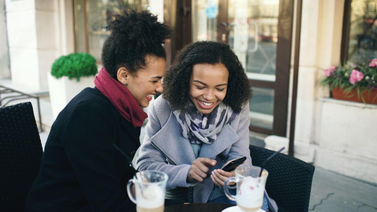 Two friends laughing over coffee at an outdoor café