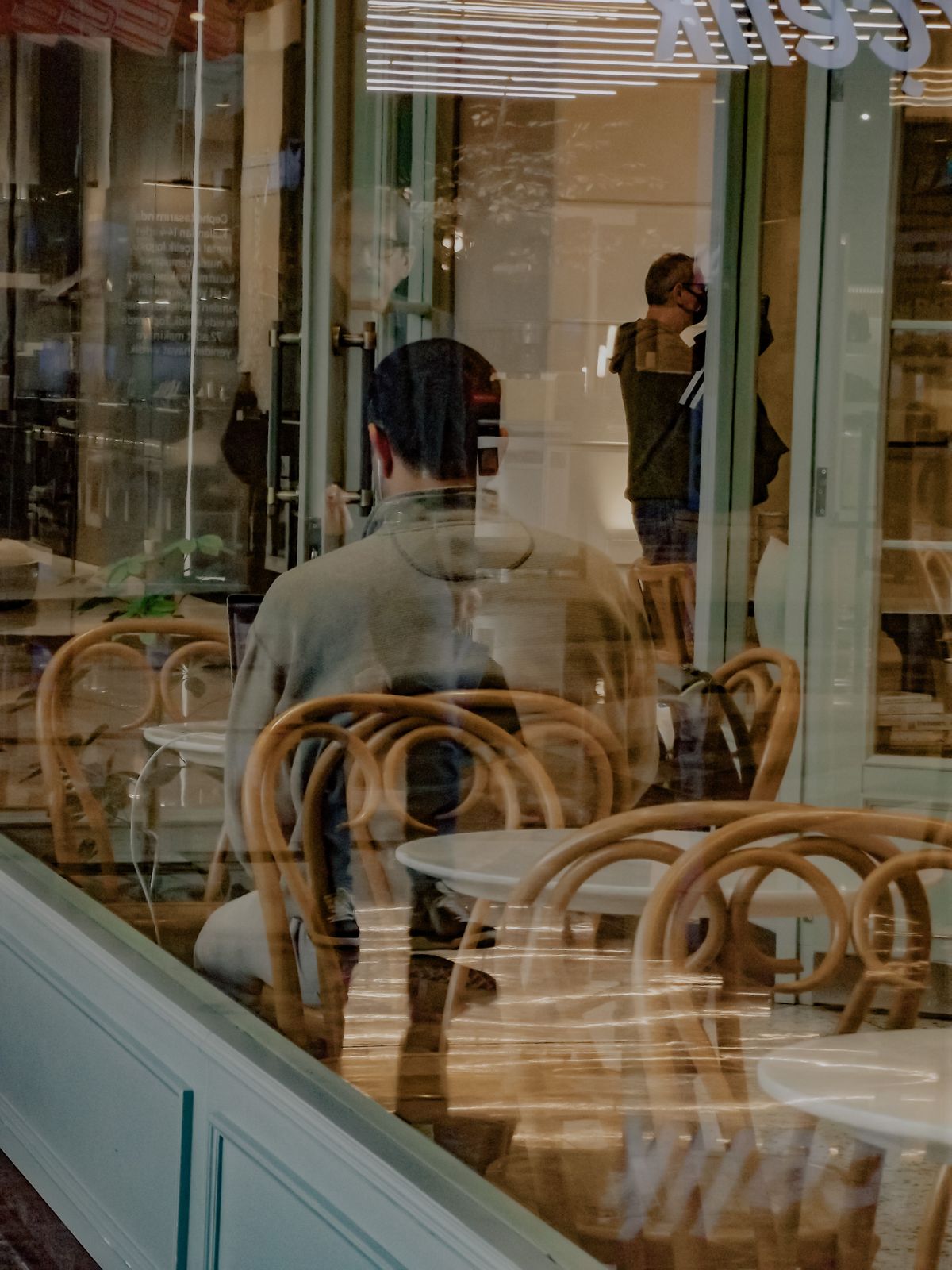 A man alone in a coffee shop, seen through the window