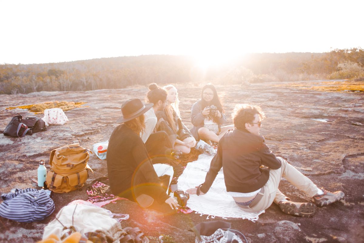A group of friends gathered outdoors for a sunset picnic