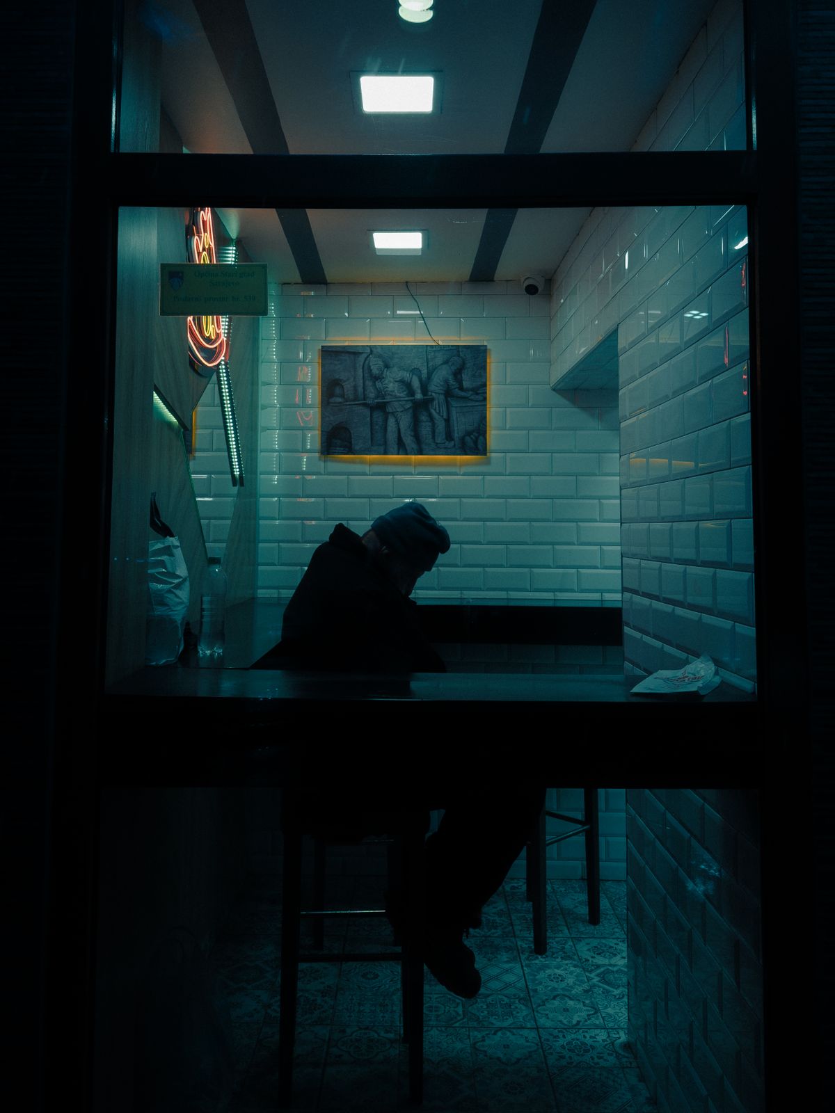 A lone figure in a warmly lit café at night