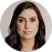 Headshot of a woman with dark hair and neutral expression wearing a grey blazer.