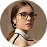 Woman with glasses wearing a black and white tank top looking slightly to the side.