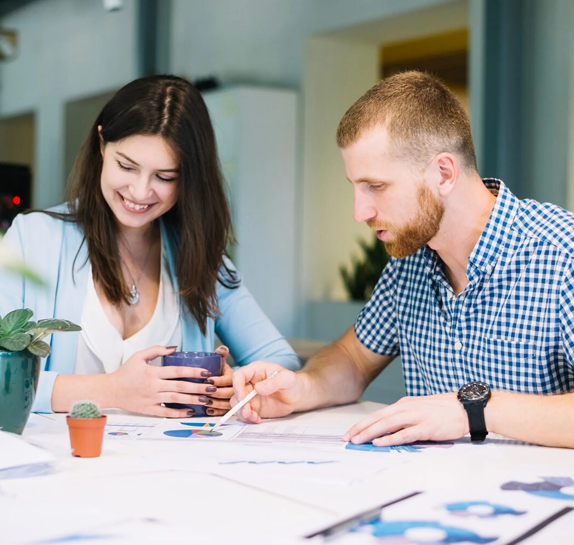 Man and woman at table reviewing documents with charts, the man pointing at a pie chart.