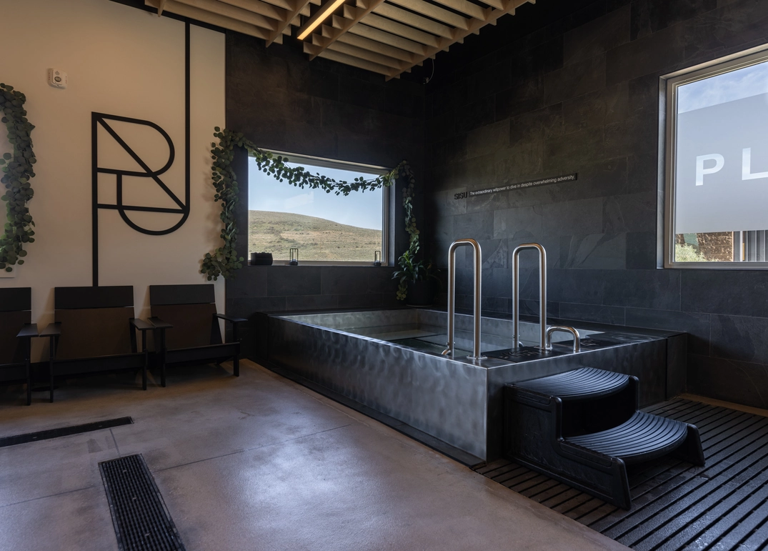 Indoor cold plunge pool beside recovery seating at Plunj Park City