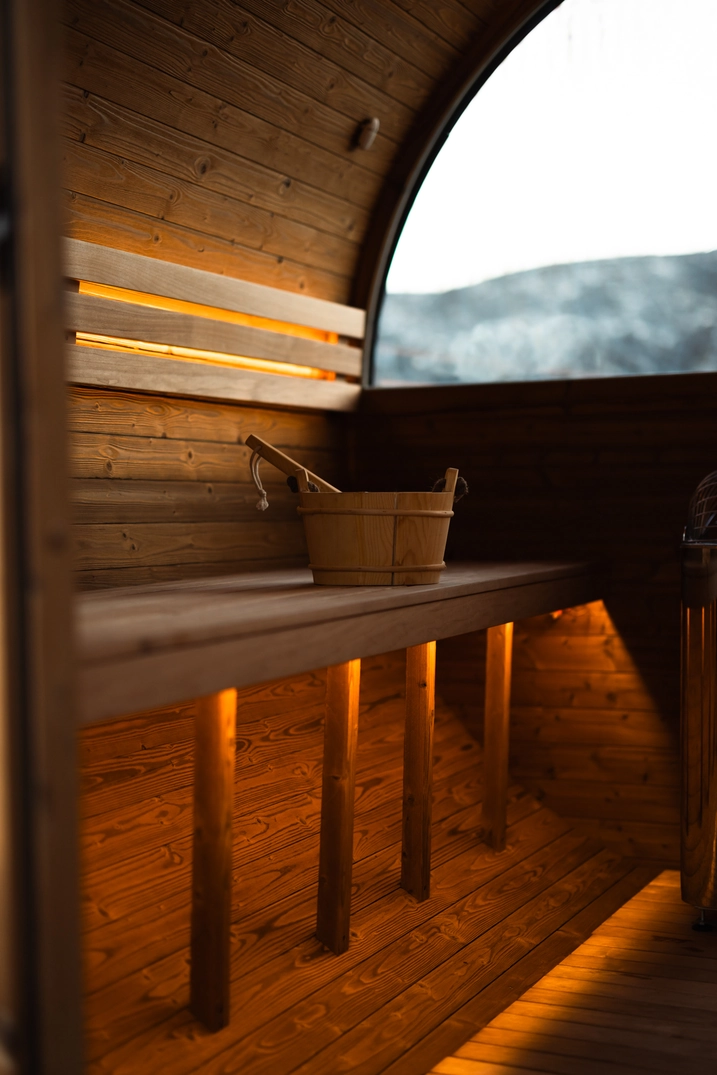 Cedar bench, sauna bucket, and mountain view inside the barrel sauna