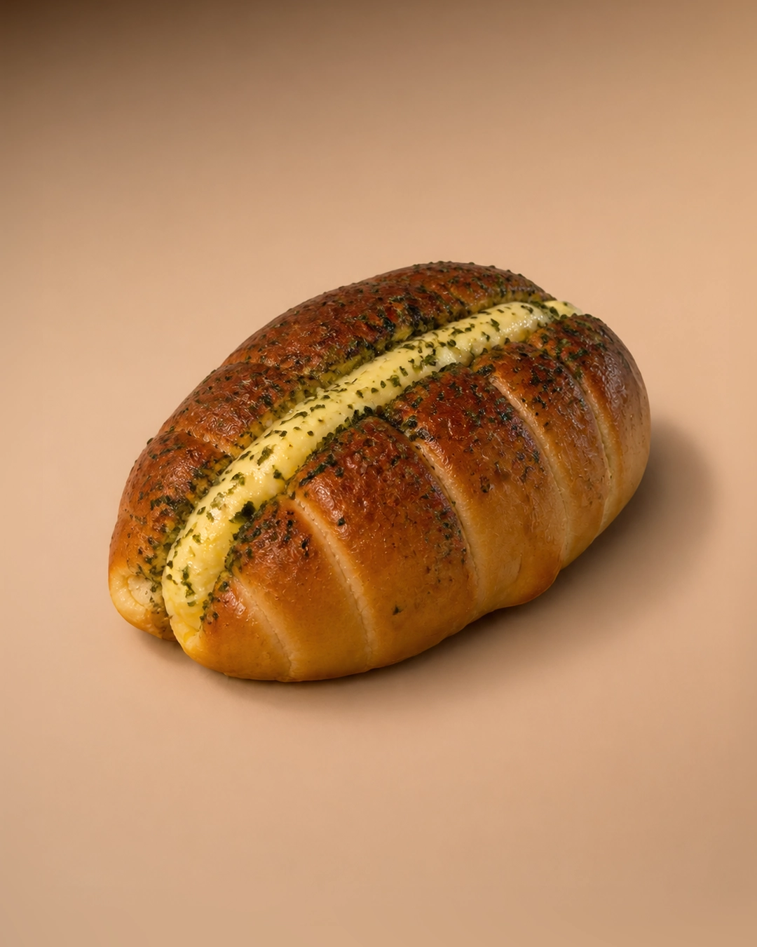 Garlic cream cheese salt bread, its crust coated in dark green garlic herb butter and split along the top with a thick piped line of cream cheese.