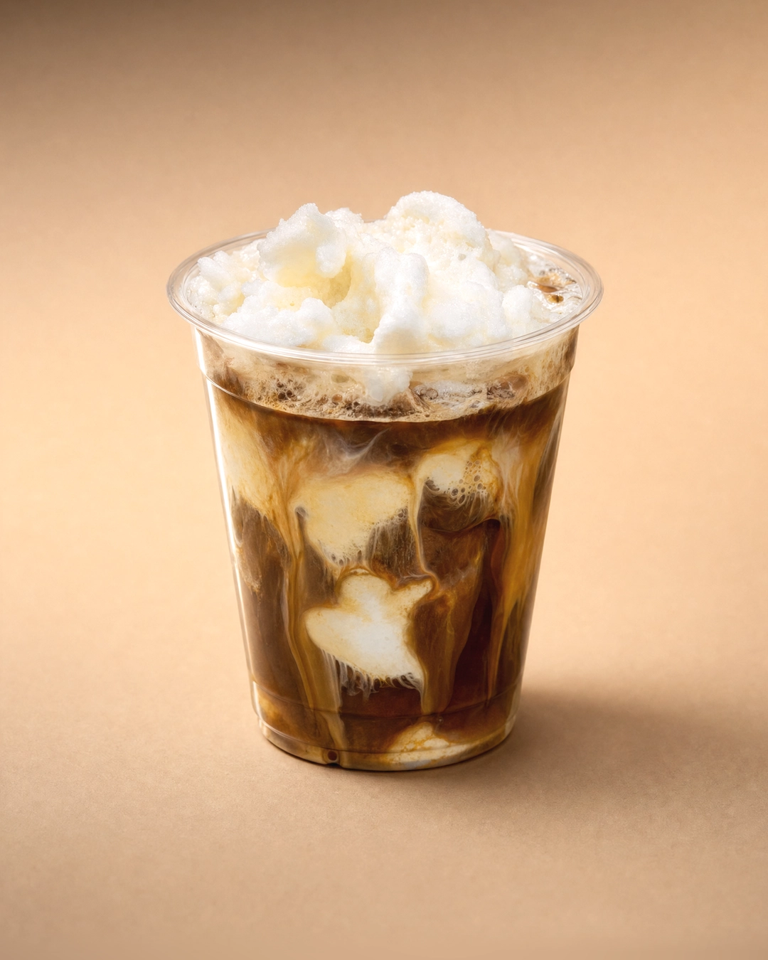 Cà phê cốt dừa (coconut coffee), dark coffee swirled with white coconut cream down the clear cup, under a rough white mound of crushed ice heaped above the rim.