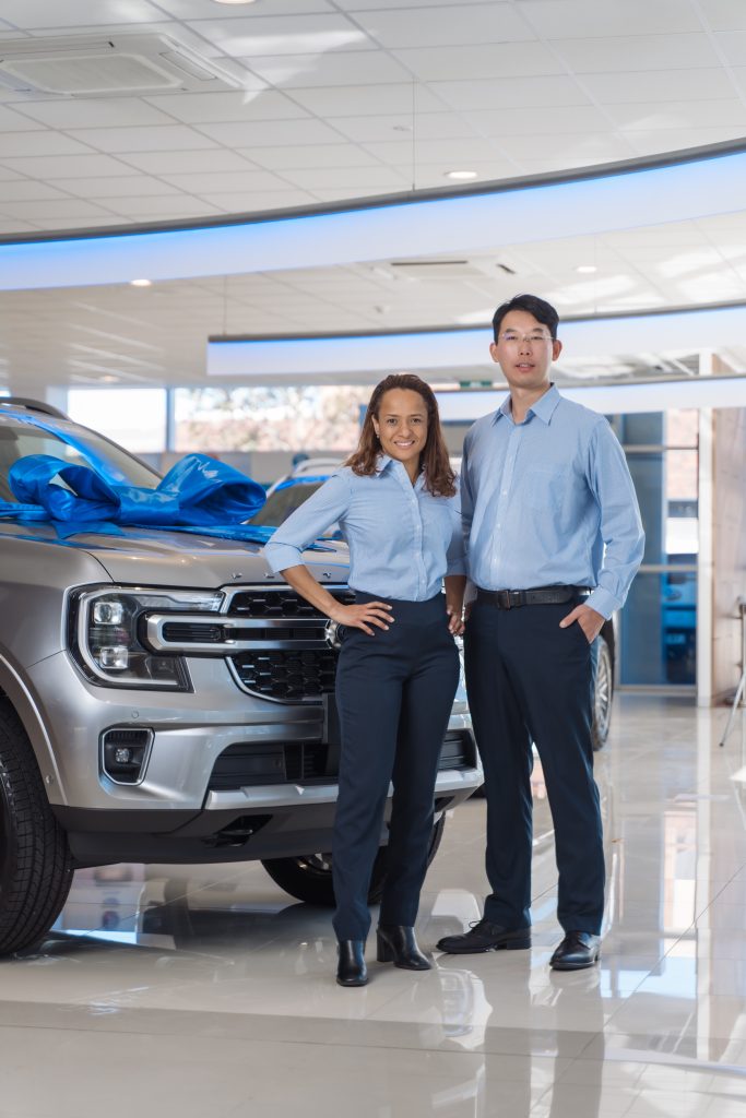 Snapshot of two Ford team members wearing light blue shirting and navy pants. new uniform