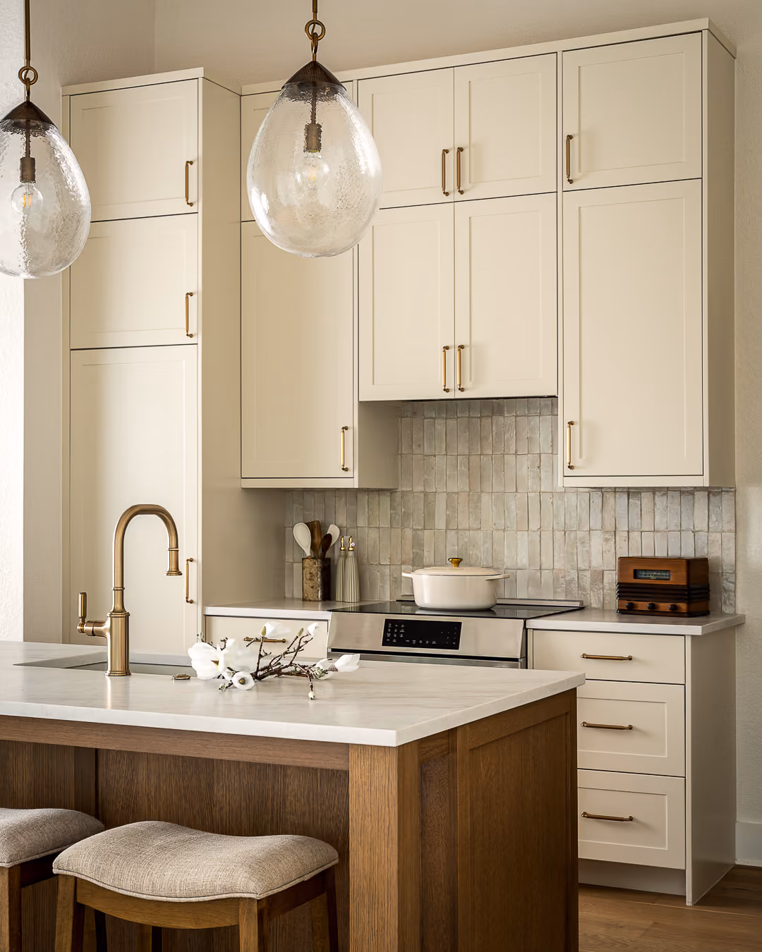 Custom kitchen cabinetry extending to the ceiling with quartz countertops and brass hardware