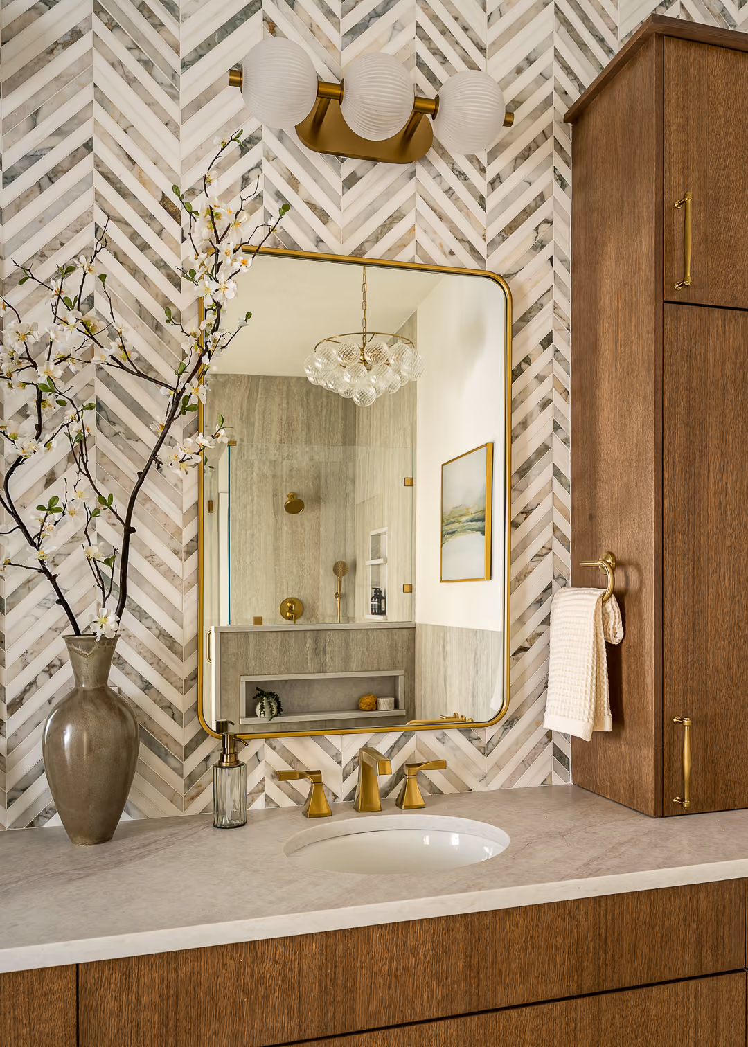 Bathroom mirror reflecting the tiled shower and warm brass fixtures