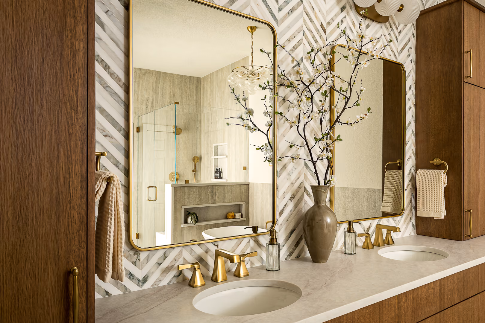Refined bathroom vanity with wood cabinetry, brass fixtures, and decorative mirrors