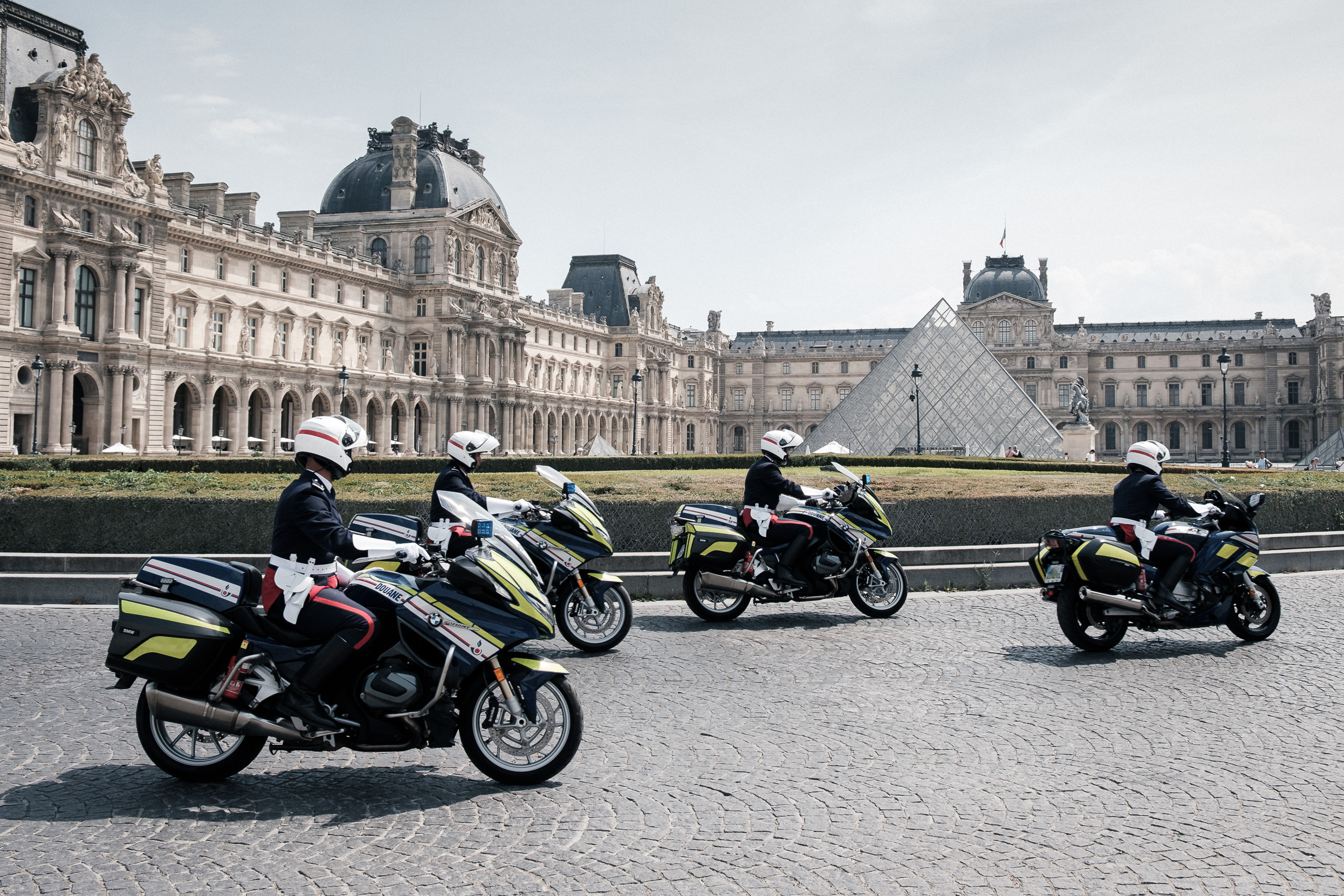 Police motorcyclists riding past the Louvre.