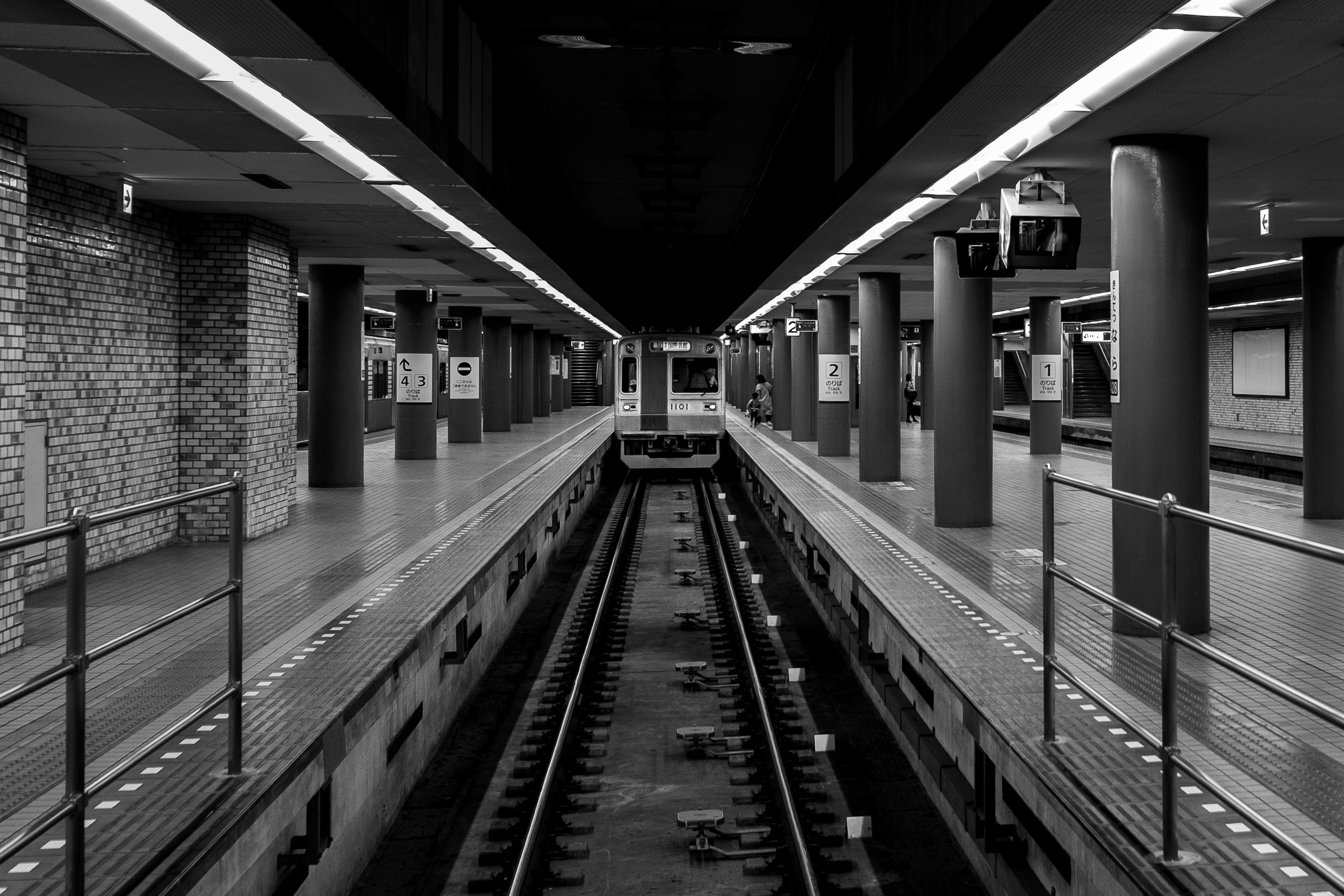 A train waits at the end of the tracks between two platforms in Kintetsu Nara Station.