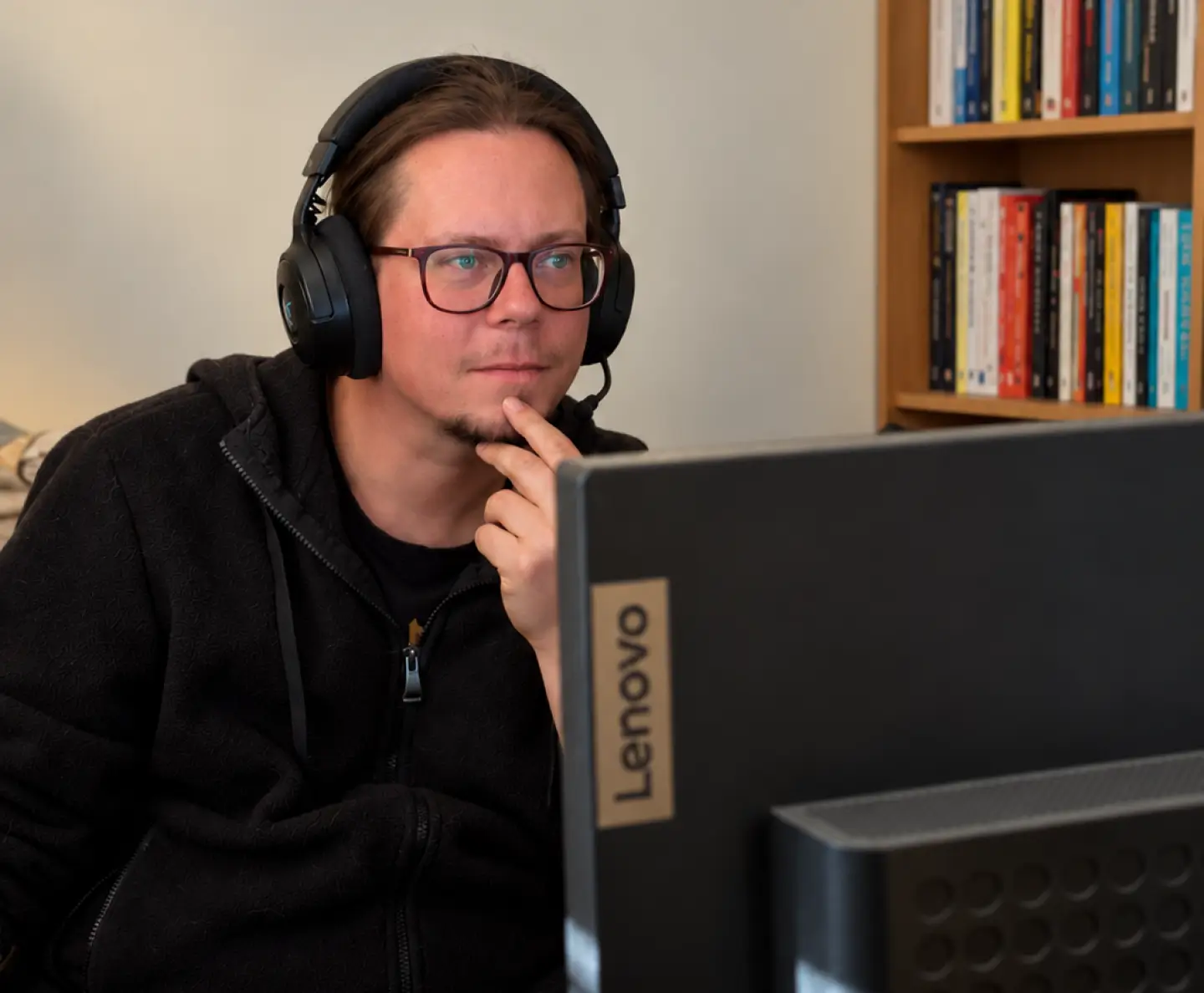Mike, Brightline co-founder, wearing a headset and listening at his desk, with a bookshelf behind him