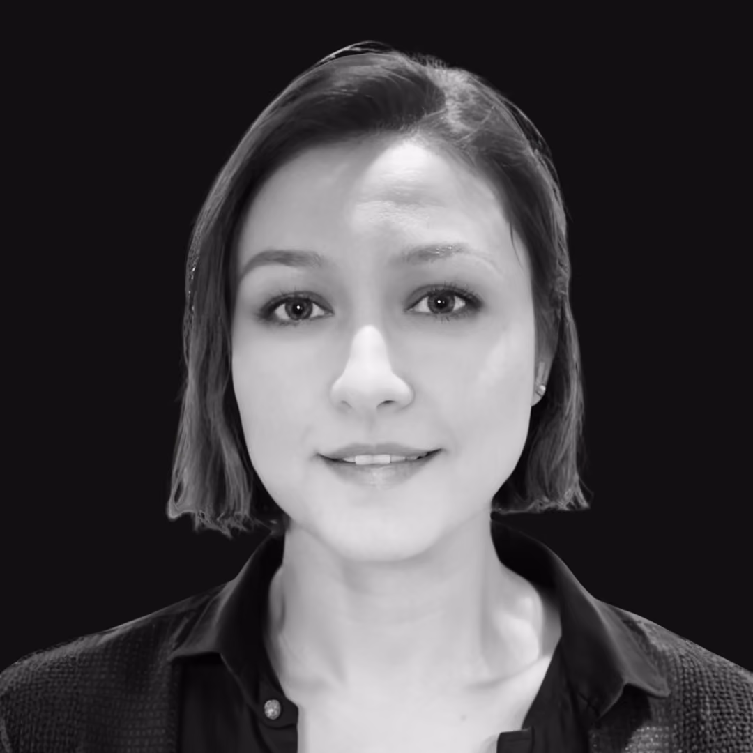 Portrait of a woman with short hair, wearing a dark collared shirt, against a plain dark background.