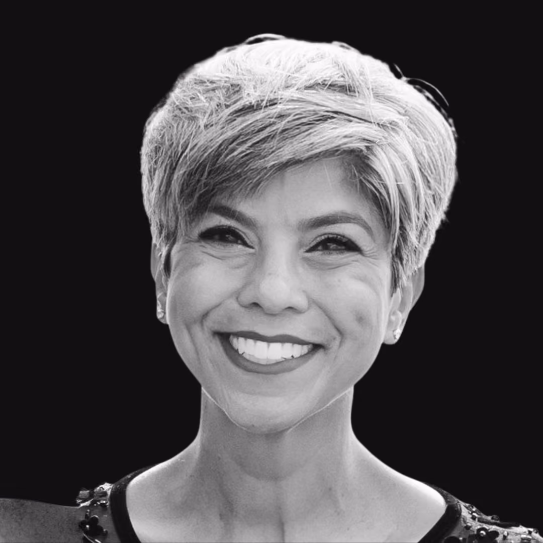 Black and white portrait of a woman with short hair smiling against a black background.