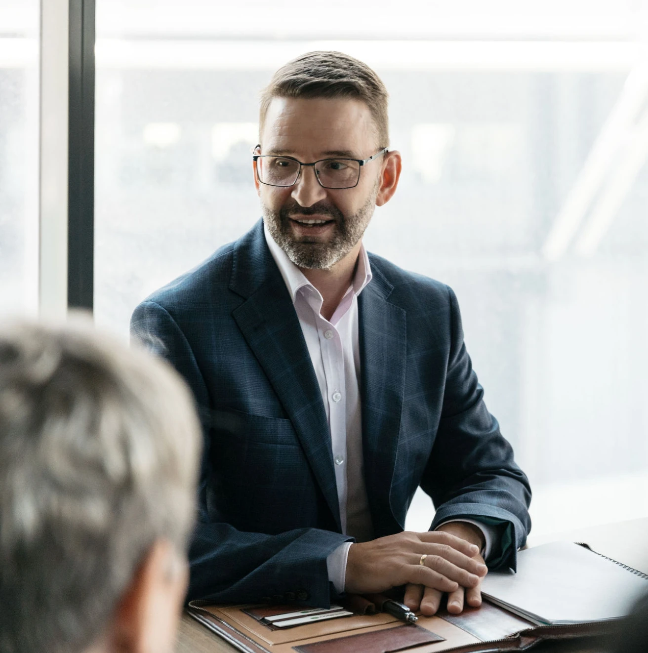 Smiling businessman talking with a colleague across a table during a meeting.