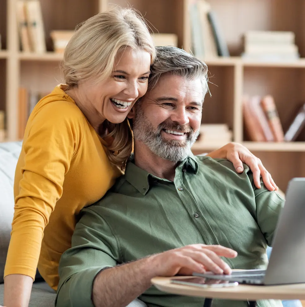 Smiling mature couple looking at a laptop together at home.