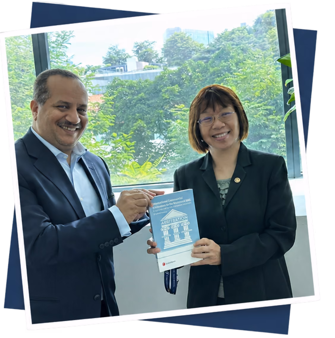 Dr Emad Hussein presenting a copy of his publication with a colleague