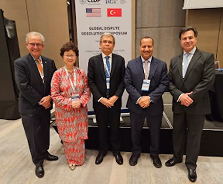 Speakers in a group photo at the Global Dispute Resolution Symposium, with US and Turkish flags
