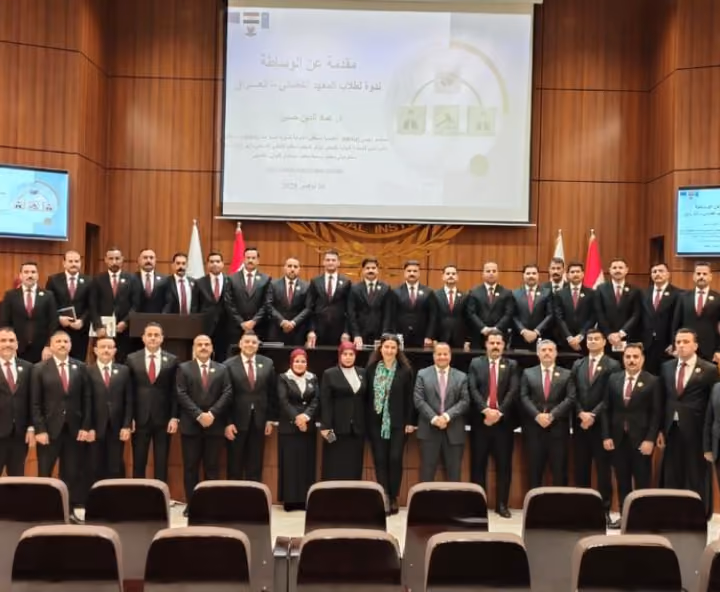Group photo of participants at a mediation course in a wood-panelled hall, with the course slide in Arabic behind them