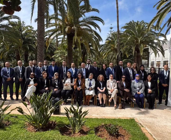 Dr. Emad Hussein posing with delegates at an international conference in a palm-filled garden.
