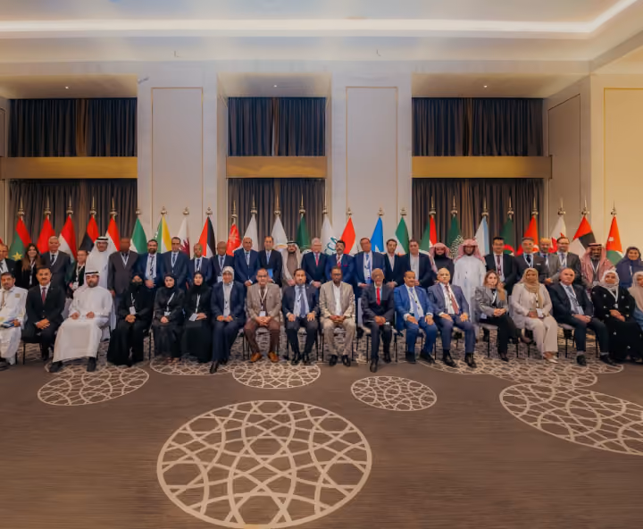 Dr. Emad Hussein posing with international delegates at a conference featuring national flags.