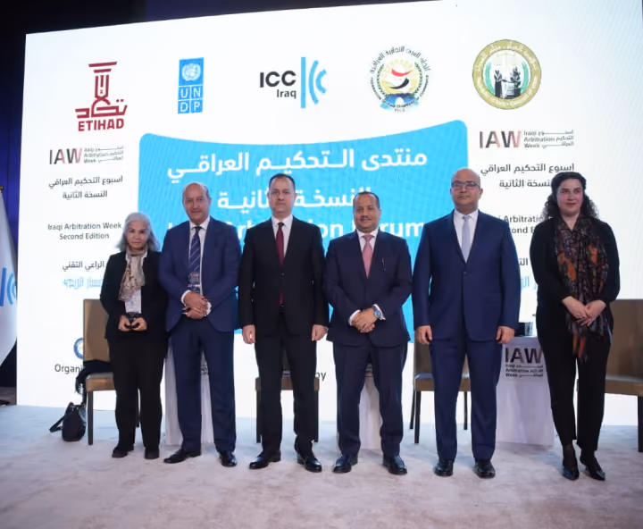 Dr. Emad Hussein with delegates at Iraqi Arbitration Week, standing in front of the event backdrop.