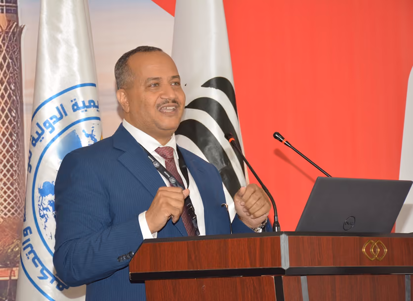 Dr Emad Hussein speaking at a podium beside the Turkish flag