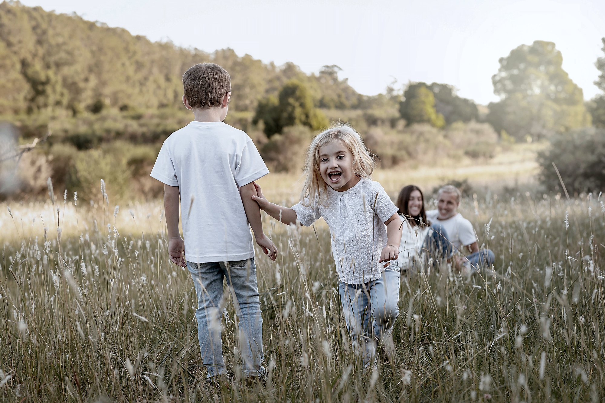 Children running through a field in afternoon light