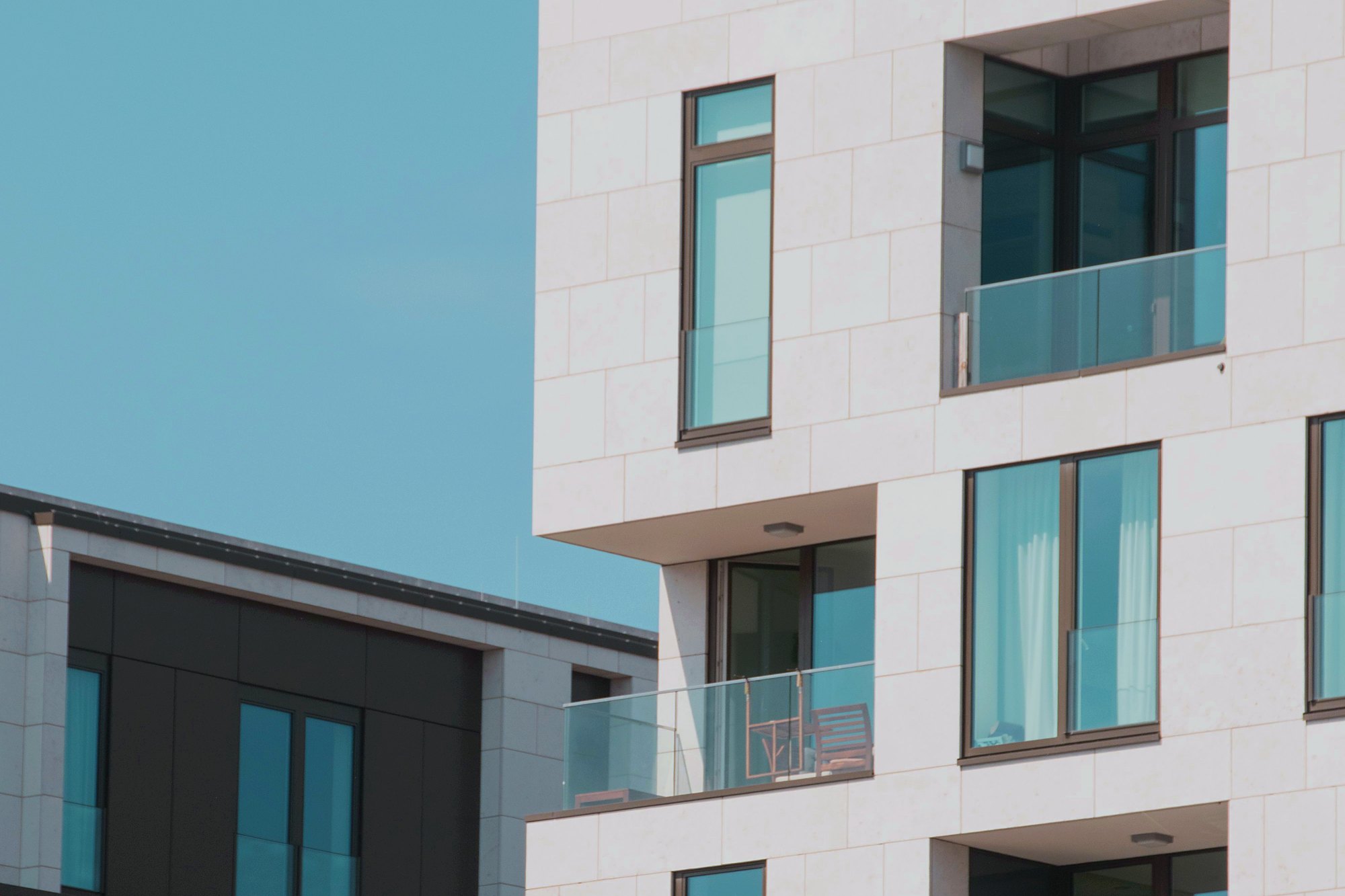 White apartment block with balconies against a clear sky