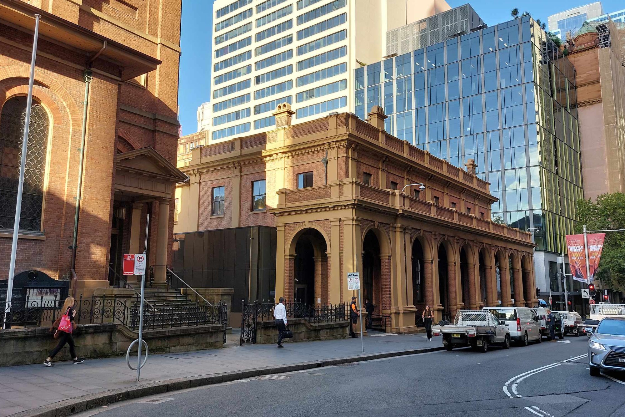 A sandstone heritage building beside modern glass towers on a Sydney city street