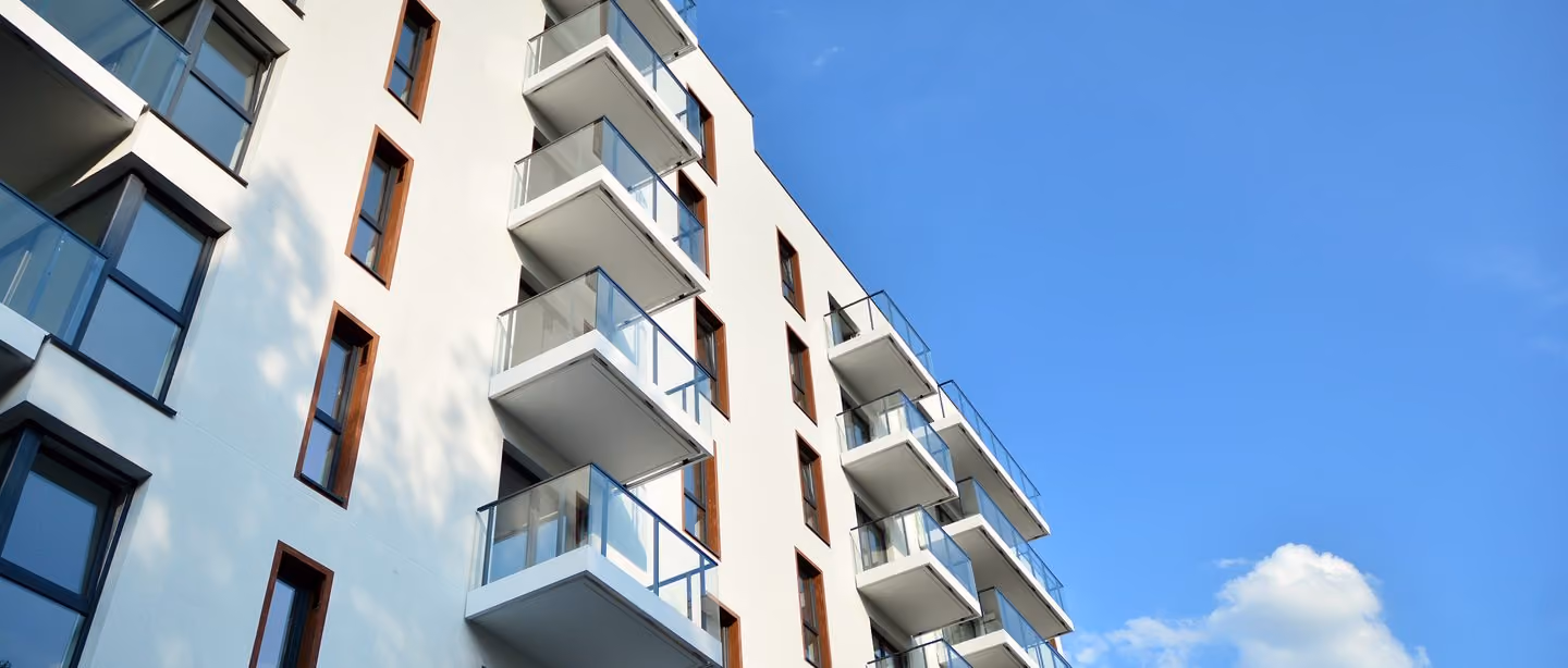 Moderne boligblokk med balkonger mot blå himmel
